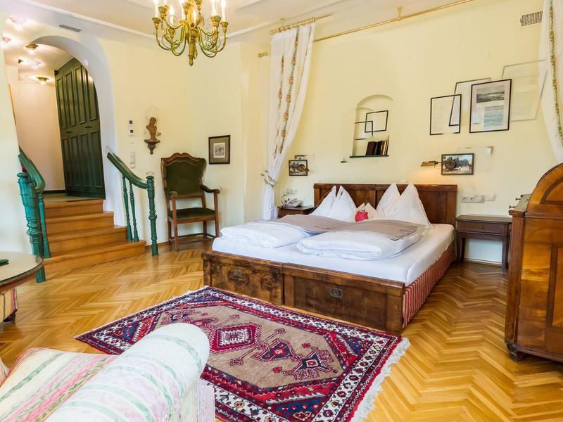 Gemütliches Schlafzimmer mit Holzboden, Teppich, Doppelbett, Stuhl, Kommode und Treppe.