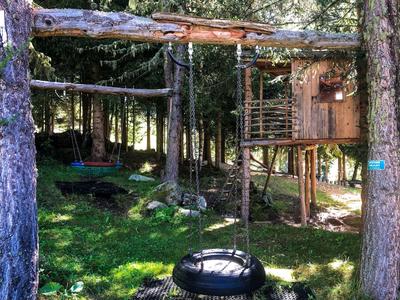 Domek na drzewie z huśtawkami z opony i drewna na polanie w lesie