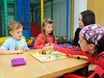 Dzieci grają w grę planszową przy drewnianym stole w kolorowej sali zabaw.