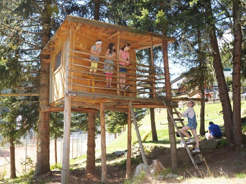 Dzieci bawiące się w drewnianym domku na drzewie w lesie