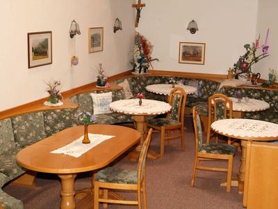 Gemütlicher Hotel-Loungebereich mit Tischen, Stühlen und gepolsterten Sitzbänken.