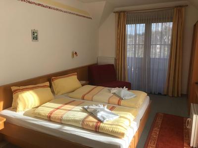 Ein helles Hotelzimmer mit zwei Betten, gelber Bettwäsche und braunen Vorhängen am Fenster.