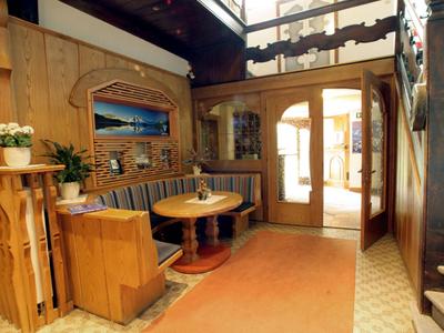 Helles Hotelfoyer mit Holzmöbeln, gemütlichem Sitzbereich und Teppichboden.