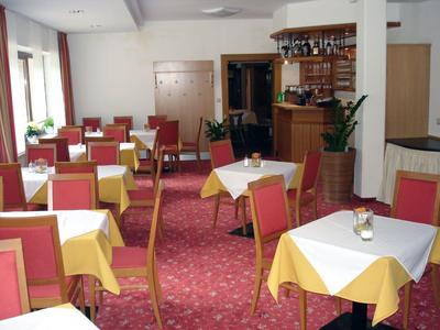 Hell eingerichteter Speiseraum mit Tischen, gelben Tischdecken und roten Stühlen in Hotelatmosphäre.