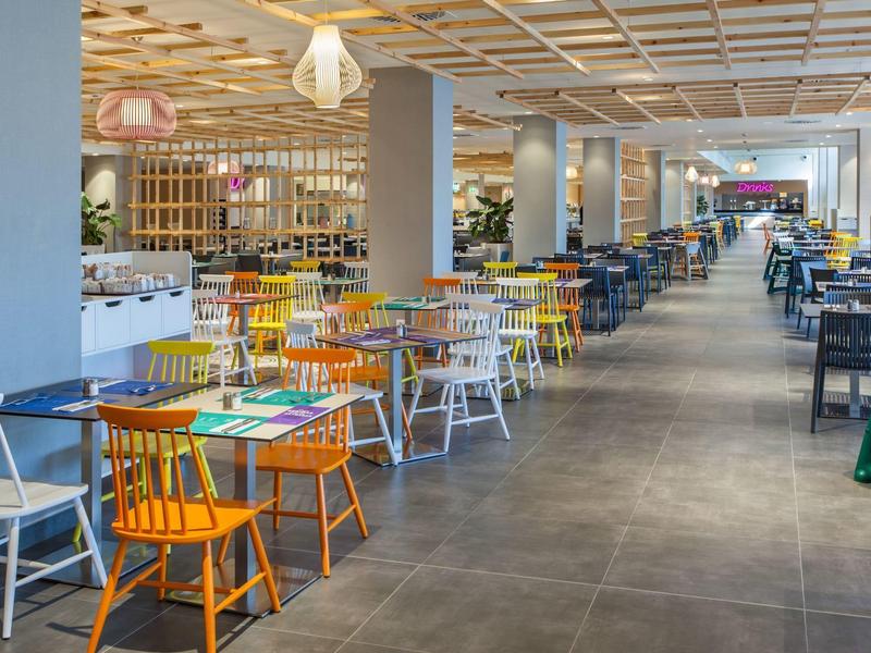 Grande salle à manger d'hôtel avec chaises colorées et décoration moderne.