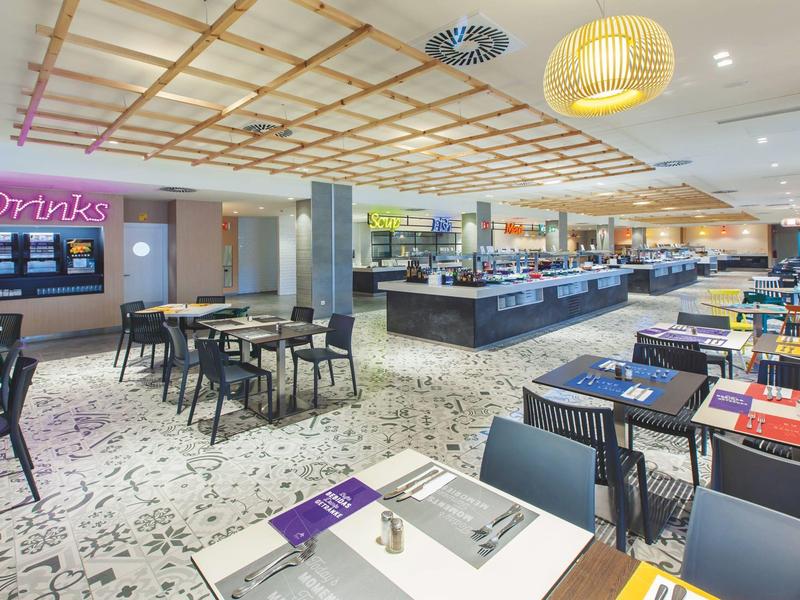 Restaurant moderne avec tables dressées et buffet dans une ambiance lumineuse.