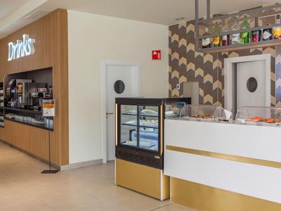 Bar del hotel con mostrador de bebidas y área de asientos, iluminación cálida y diseño moderno.