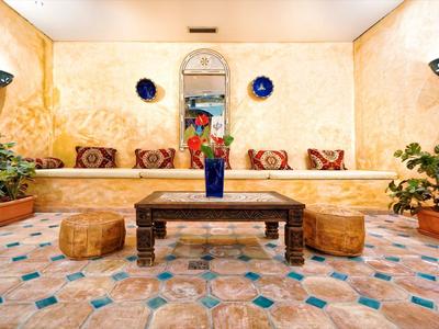 Cozy seating area with cushions, plants, and decorative wall plates in a warm, tiled room.