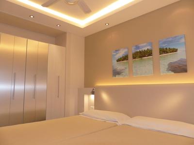 Modern hotel room with two beds, large wardrobe, ambient lighting, and wall art above the beds.