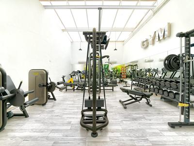 Hell beleuchteter Fitnessraum mit vielfältigen Trainingsgeräten und Spiegeln an der Wand