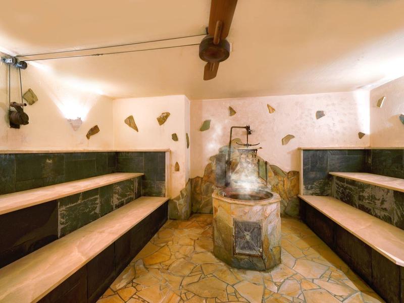 Cozy sauna room with wooden benches, stone floor, and a central heater.