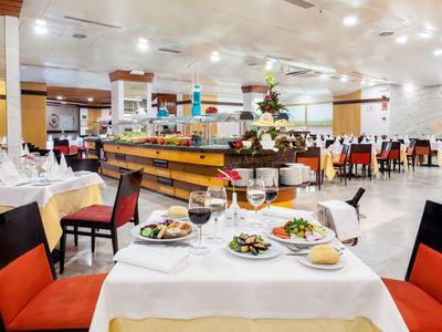 Restaurante elegante con mesas puestas y sillas rojas en ambiente iluminado