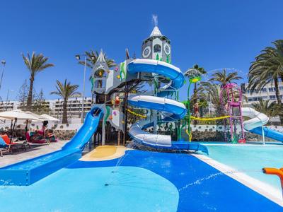 Parc aquatique coloré avec toboggans et palmiers par une journée ensoleillée.