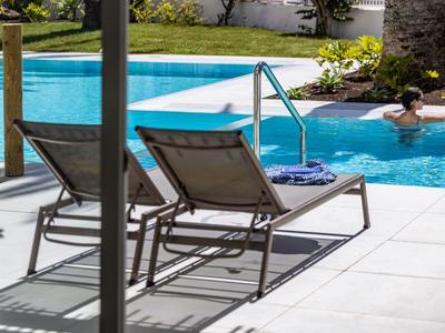 Due lettini accanto a una piscina con una persona che si rilassa nell'acqua.