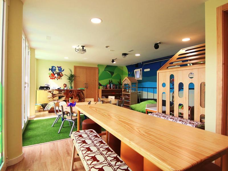 Colorful kids' room with large wooden table, toys, and seating.