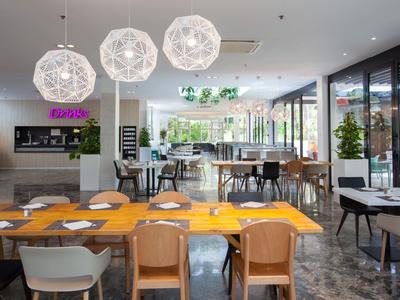 Modern restaurant with multiple tables and chairs, large windows, and decorative lamps.