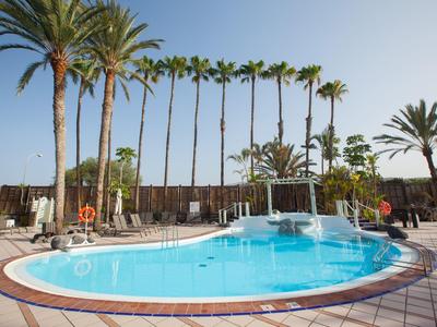 Ronde buitenzwembad met blauw water en palmbomen in hotelomgeving bij zonnig weer.