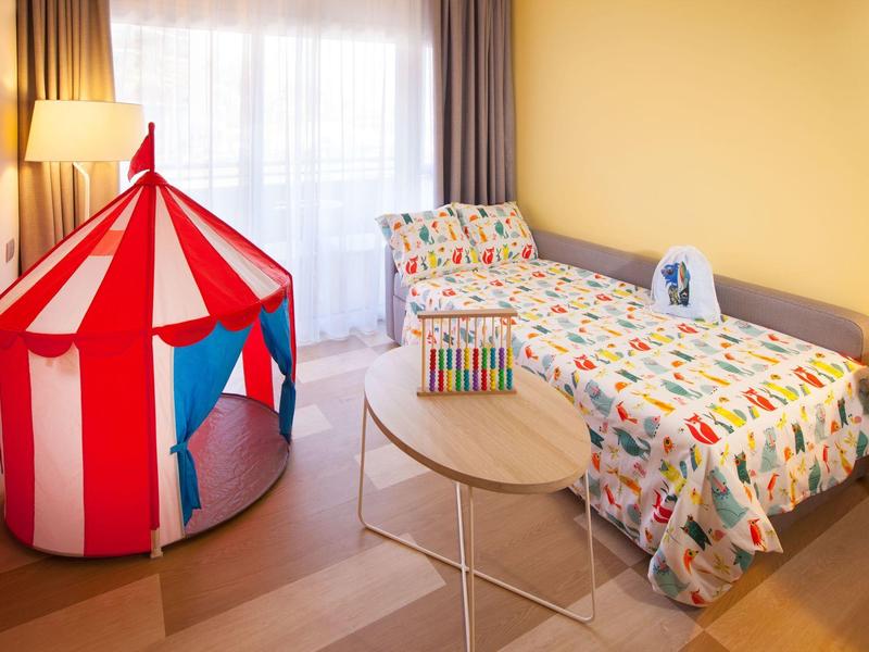 Kinderkamer met bed, kleurrijke tent en nachtkastje in warm licht