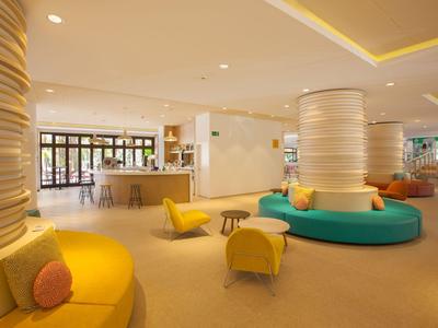 Jasny hol hotelowy z nowoczesnymi, kolorowymi miejscami do siedzenia i dużymi kolumnami.