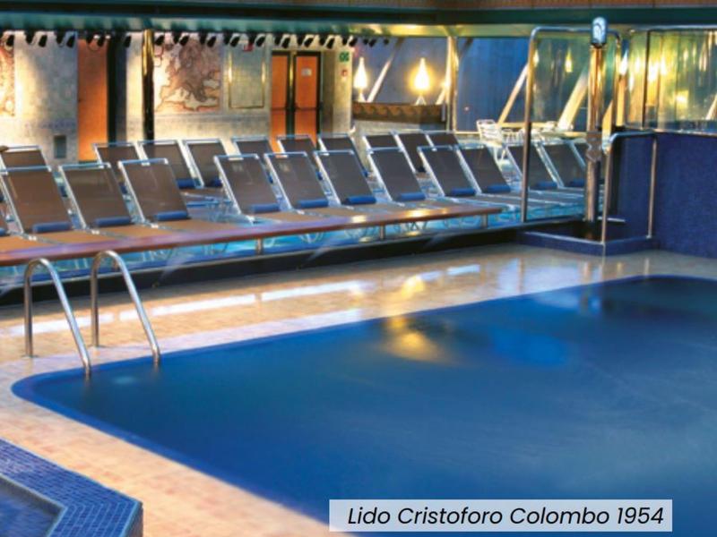 Piscina cubierta con luz cálida y tumbonas alineadas en un hotel.