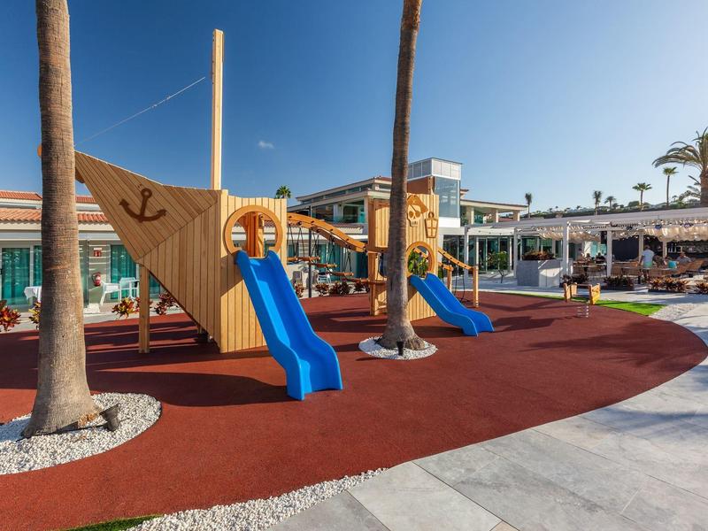 Outdoor playground with slides and a ship-shaped climbing structure at a resort.