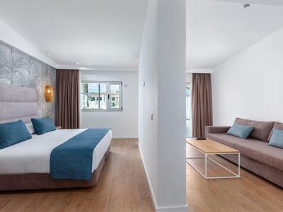 Modern hotel room with bed, blue accents, and separate sitting area with sofa