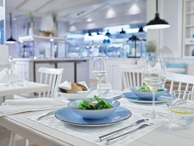 Lichte, moderne eetkamer met gedekte tafels en verse salades op blauwe borden.