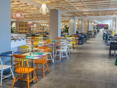 Large modern dining area with colorful chairs and long tables in a bright setting.