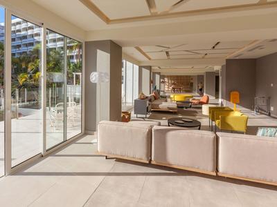 Bright hotel lounge with large windows, comfortable sofas, and modern furnishings.