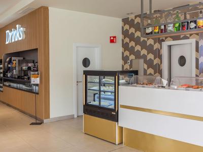 Area moderna dell'hotel con banco bevande e bar, design luminoso e pulito.