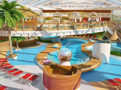 Indoor hotel area with pool, palm trees, and lounge chairs under glass roof