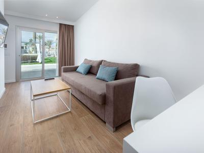 Modern living room with brown sofa, wooden floor, and garden view through glass sliding door.