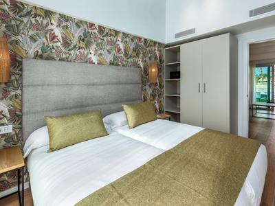 Modern hotel room with double bed, floral wallpaper, and balcony view.