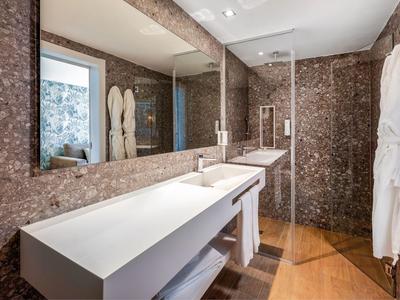Modern hotel bathroom with large mirror, double sinks, and marble tiles.