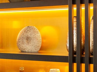 Display cabinet with decorative vases and objects in warm yellow light.