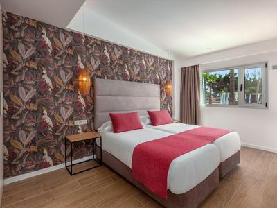 Chambre d'hôtel moderne avec deux lits simples, mur avec motif floral et sol en bois