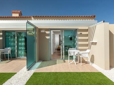 Entrada moderna de habitación de hotel con puerta corredera de vidrio y terraza soleada.
