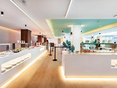 Restaurante buffet moderno y luminoso con suelo de madera y mostradores blancos iluminados.