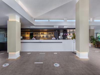 Recepción moderna de hotel con mostrador blanco y columnas iluminadas