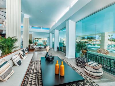 Área interior moderna con asientos, cojines y vistas al agua y barcos.