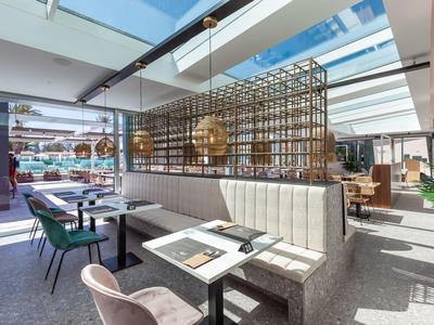 Ristorante moderno con tetto in vetro, sedute comode e tavoli eleganti.