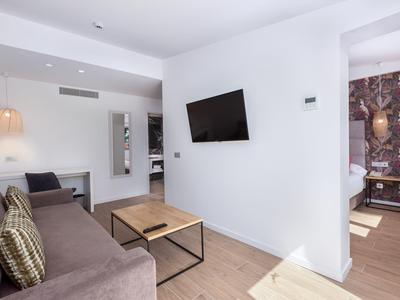Modernes Hotelzimmer mit Sofa, TV an der Wand und Holzboden