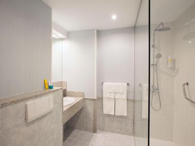 Modern bathroom with shower, towels, and light-colored walls.