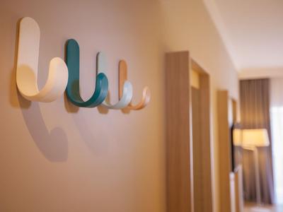 Modern wall hooks in various colors in a bright hotel hallway.