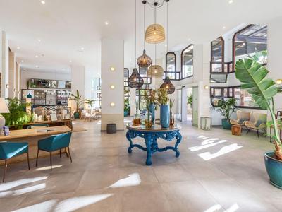 Hall d'hôtel lumineux et moderne avec espace ouvert et accents de plantes.