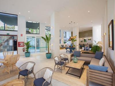 Jasna, nowoczesna lobby hotelowa z miejscami do siedzenia, roślinami i dużymi oknami.