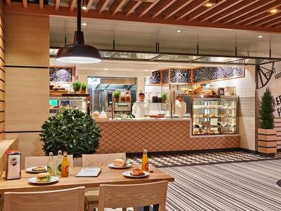 Comptoir de restaurant d'hôtel moderne avec coin salon et éclairage chaleureux.