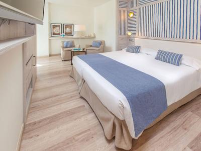 Moderne hotelkamer met groot bed, blauw-witte accenten en zithoek.