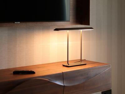 Habitación moderna con lámpara de pared, televisor y taburete frente a estante de madera