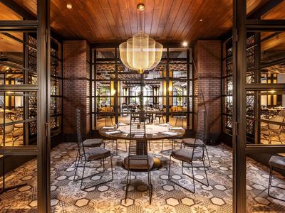 Gemütlicher Restaurantbereich mit Holzdecke, runden Tischen, Stühlen und warmem Licht.